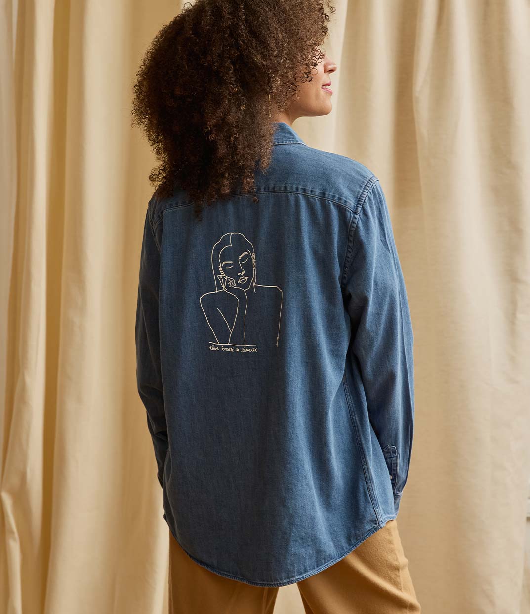 Une femme portant une chemise en denim Thémis de Leonor Roversi, marque locale lyonnaise de mode féminine et éthique, avec un visuel inspiré de la justice, symbole d’empowerment et de savoir-faire français.