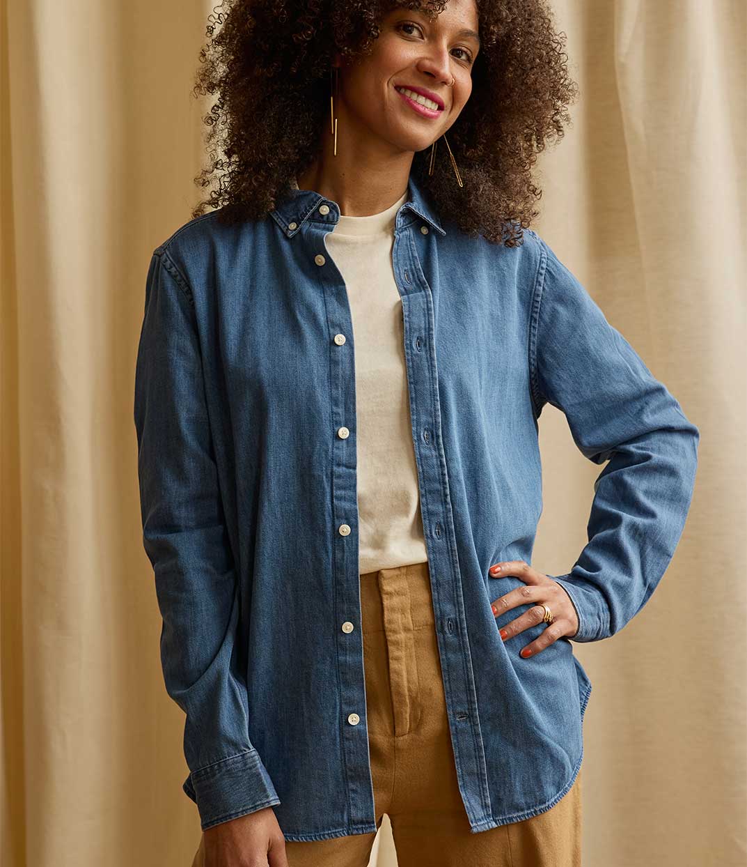 Une femme inspirante portant une chemise ouverte en denim Thémis de Leonor Roversi, marque locale lyonnaise de mode féminine et durable, avec un visuel inspiré de la justice, symbole d’empowerment et de savoir-faire français.