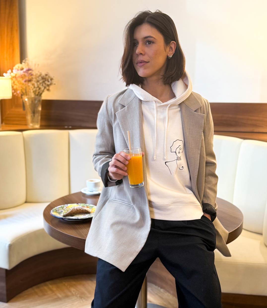 Femme portant un hoodie en coton bio écru, imprimé noir d'une femme forte avec l'inscription "battante". accompagné d'un blazer oversize. Modèle Klimt, conçu et imprimé à Lyon par la marque éthique Leonor Roversi.