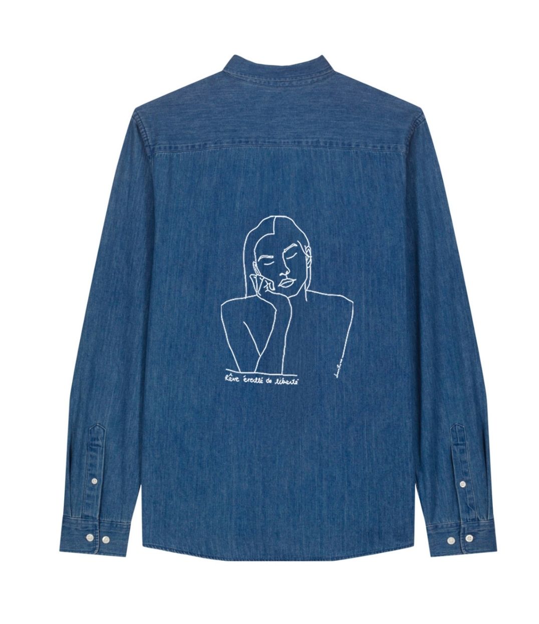 Mock-up d'une chemise pour femme ample en coton bio denim. Le vêtement présente un imprimé blanc minimaliste d’un visage féminin aux yeux clos, accompagné de l’inscription « rêve éveillé de liberté ». Modèle Thémis, conçu et imprimé à Lyon par la marque éthique Leonor Roversi.