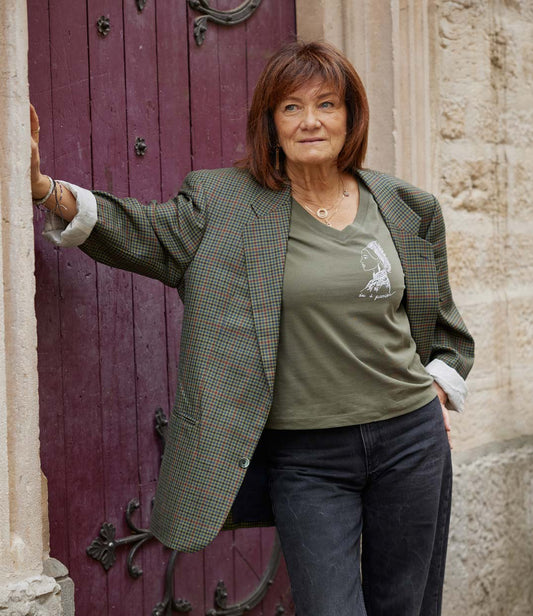 Femme portant un t-shirt ample à col v en coton bio kaki. Le vêtement présente un imprimé blanc représentant une guerrière japonaise, accompagnée de l’inscription « âme d'une guerrière ». Modèle Benten, conçu et imprimé à Lyon par la marque éthique Leonor Roversi.