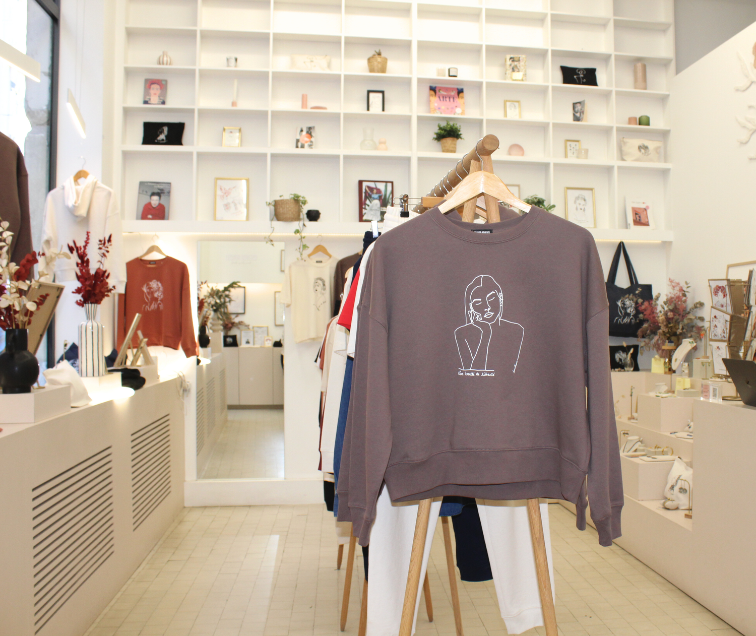 Intérieur de la boutique lyonnaise Leonor Roversi, espace engagé dédié à la mode éthique. Sweats féminins en coton bio exposés sur portants, ambiance chaleureuse et responsable, créations engagées imaginées et fabriquées à Lyon.
