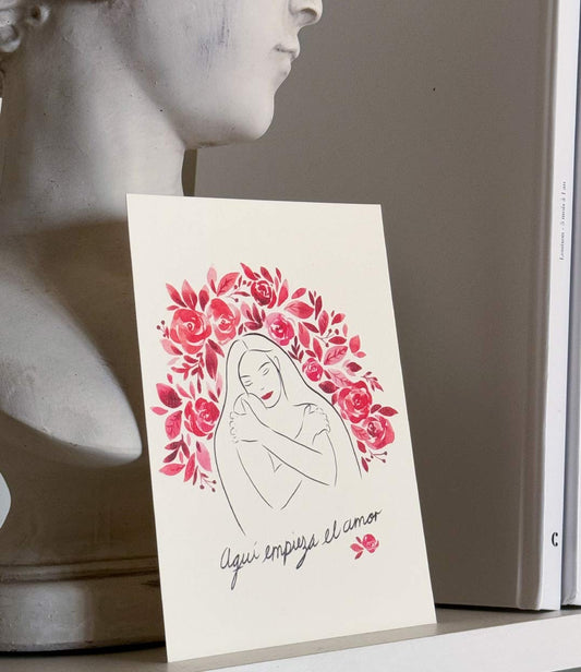 Affiche Leonor Roversi illustrant une femme entourée de fleurs roses et le message 'Aquí empieza el amor', créée en collaboration avec le Mexique pour célébrer l'amour de soi. Édition limitée de papeterie symbolique pour la Saint-Valentin, disponible en boutique et sur l'e-shop.