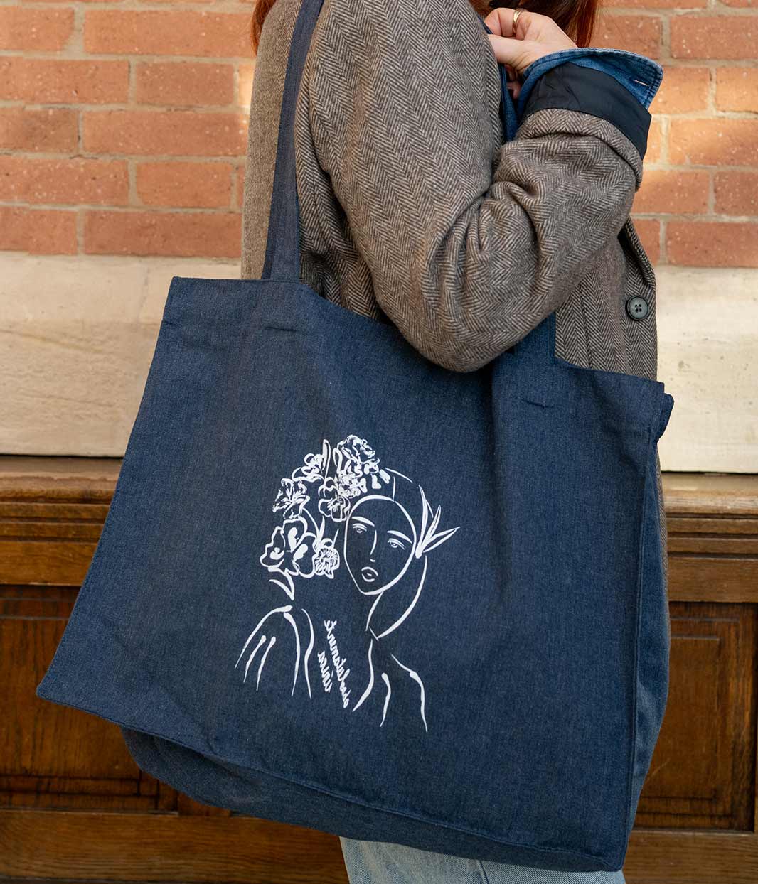 Cabas Denim avec imprimé rose illustrant une silhouette féminine avec des fleurs suivi de l'inscription "absolumente única". Modèle Unica, conçu et imprimé à Lyon par la marque éthique Leonor Roversi.