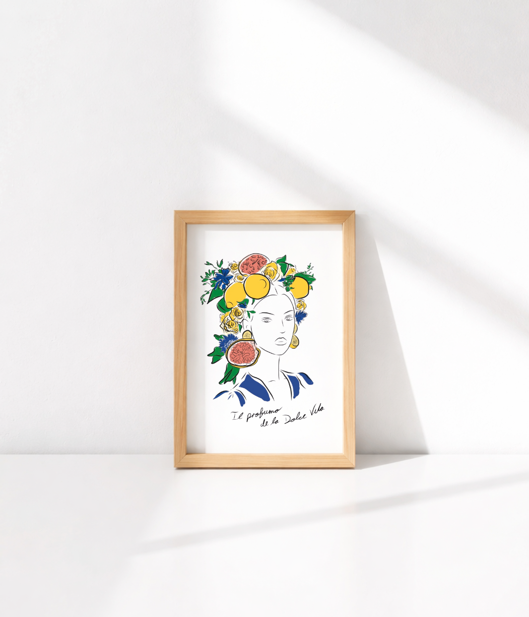 Carte postale illustrée représentant une femme avec des fruits (citrons, pamplemousses) et des fleurs colorées dans les cheveux. Texte manuscrit "Il profumo de la Dolce Vita" en bas de l’illustration. Posée sur une enveloppe kraft et un fond tressé naturel.