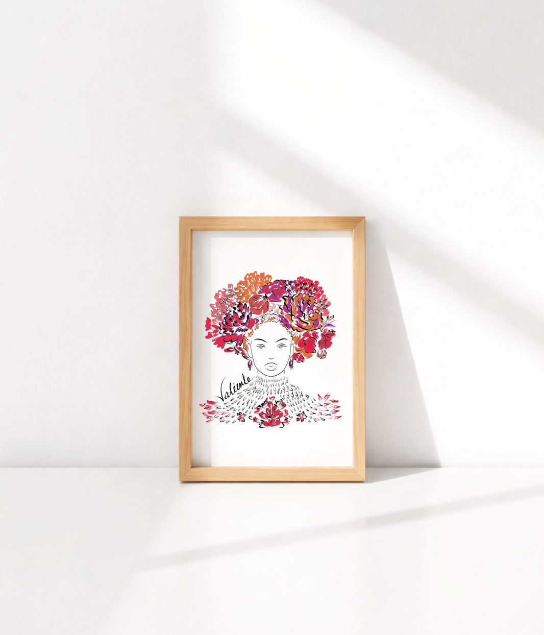 Carte postale illustrée d'une femme forte avec des fleurs rouges et oranges dans les cheveux représentant la première reine nigériane accompagnée de l'inscription  "Valiente" sur le côté. Modèle Valiente, conçue et imprimée à Lyon par la marque éthique Leonor Roversi.