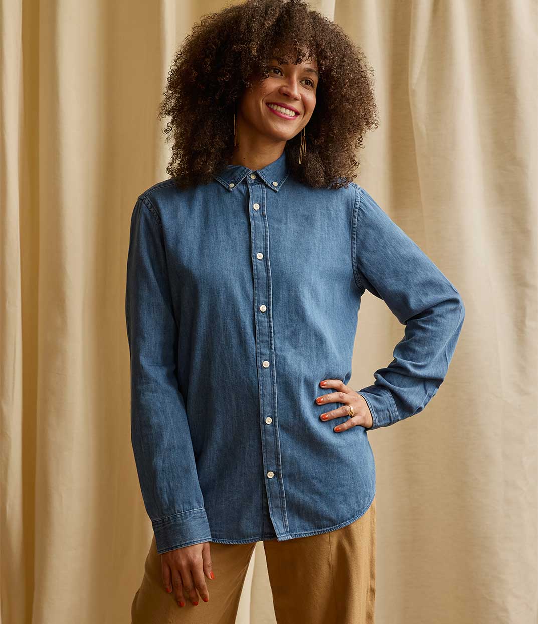 Femme portant la chemise en denim fermée Thémis vu de devant de la marque lyonnaise Leonor Roversi, pièce de mode responsable et inclusive fabriquée localement, en coton bio, alliant simplicité et engagement pour l’égalité des genres et le savoir-faire français.