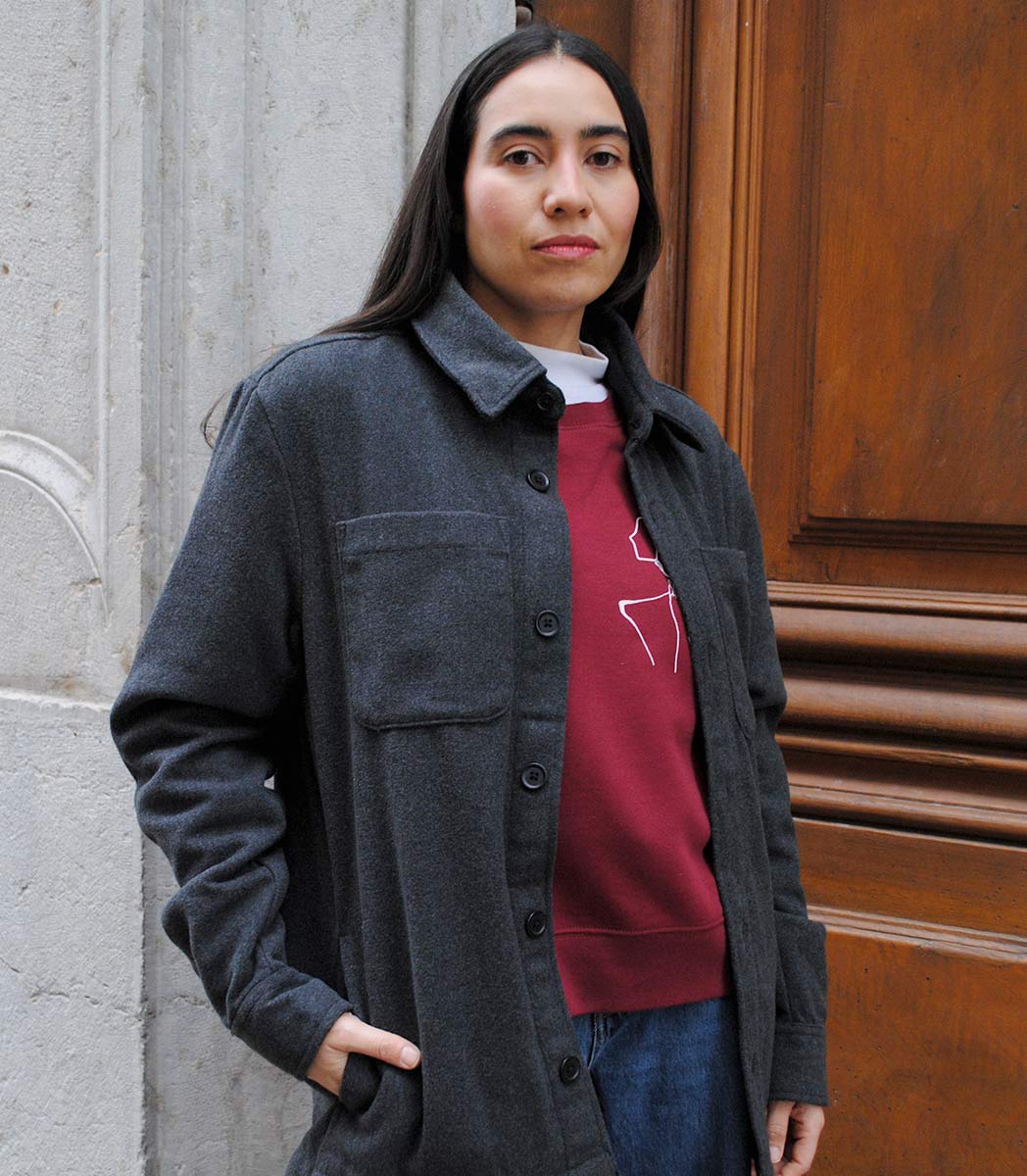 Veste ALMA LIBRE Leonor Roverssi en polyester recyclé certifié GOTS et FairWear, coupe droite gris foncé, portée par une femme confiante. Vêtement éthique brodé à Lyon, inspiré de la liberté intérieure et de la résilience féminine.