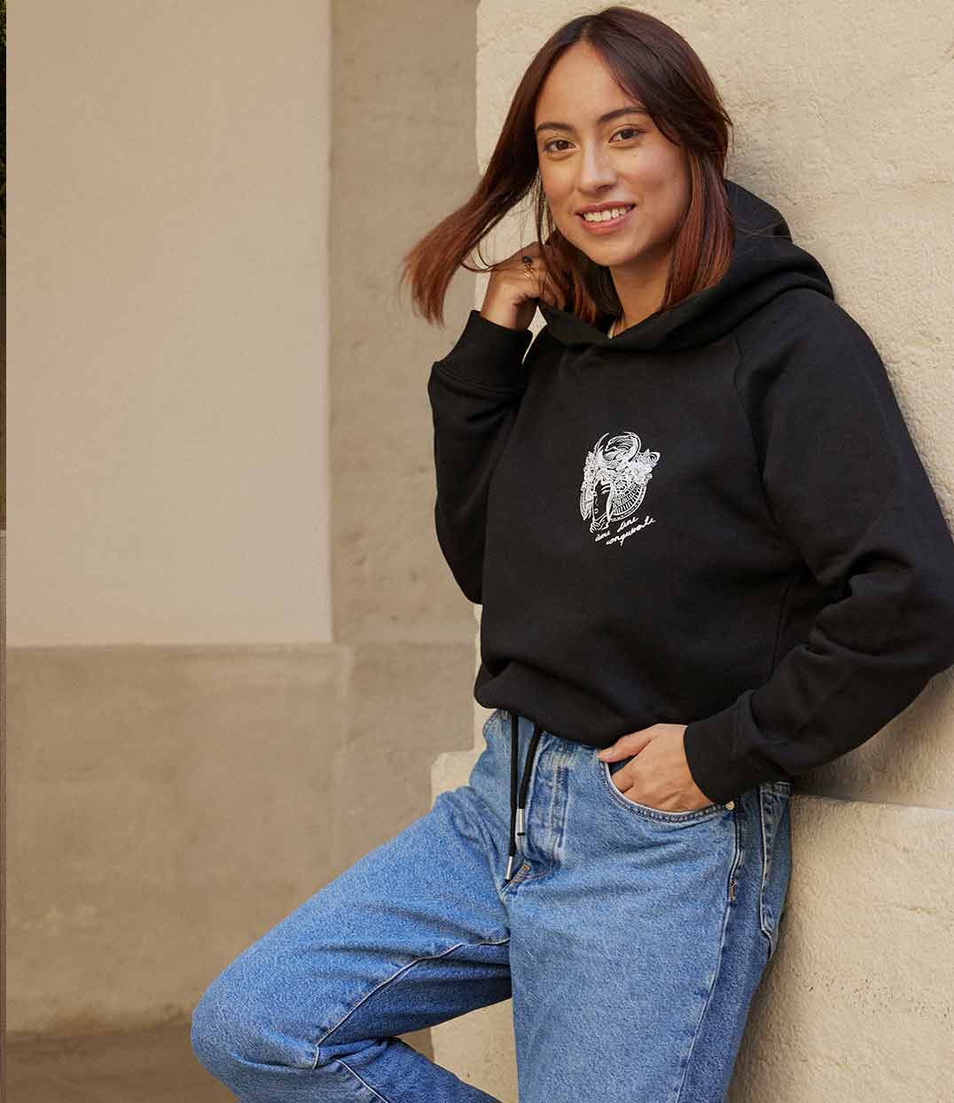 Femme portant un hoodie noir en coton bio avec un imprimé blanc représentant une femme samouraï, avec l'inscription "âme d'une guerrière". Modèle Gozen, conçu et imprimé à Lyon par la marque éthique Leonor Roversi.