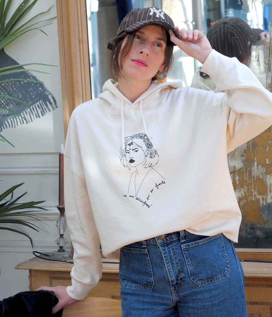 Hoodie LUPITA Léonor Roverssi en coton bio certifié GOTS et polyester recyclé, porté par une femme libre et confiante. Sweat à capuche éco-responsable, sérigraphie artisanale lyonnaise, symbole de féminité forte et indépendante.