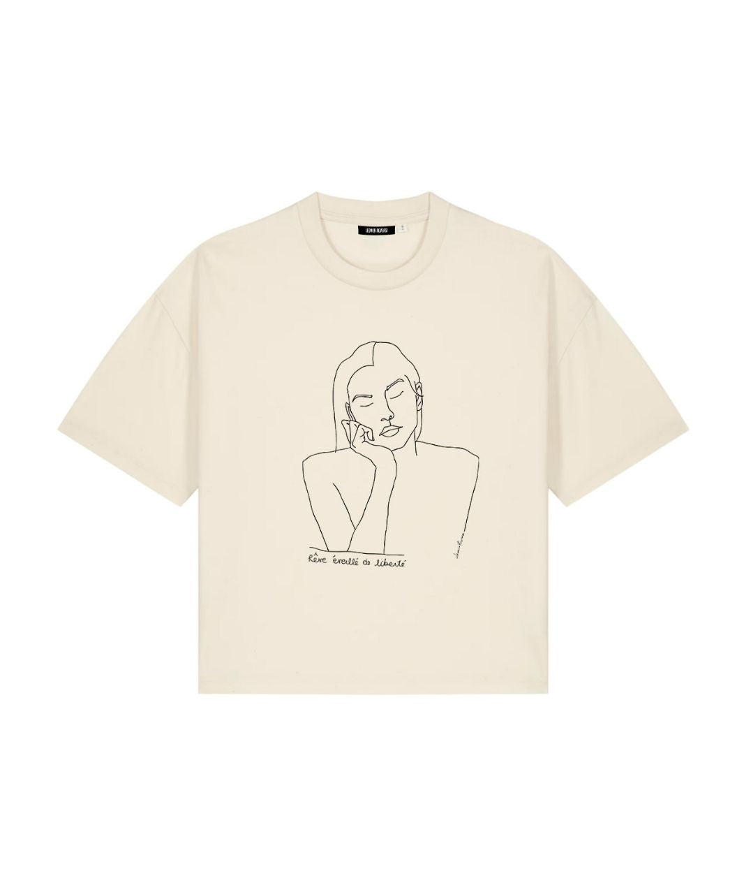 Mock-up d'un t-shirt ample pour femme en coton bio écru. Le vêtement présente un imprimé noir minimaliste d’un visage féminin aux yeux clos, accompagné de l’inscription « rêve éveillé de liberté ». Modèle Thémis, conçu et imprimé à Lyon par la marque éthique Leonor Roversi.