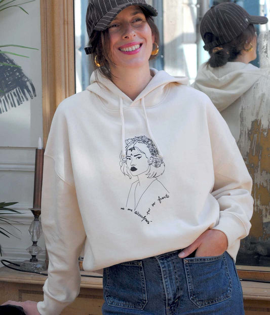 Femme portant le hoodie LUPITA écru en coton bio, illustration féminine sérigraphiée à Lyon, incarnant la force féminine et la liberté de choix. Sweat éthique à capuche, coupe décontractée, mode responsable et engagée.