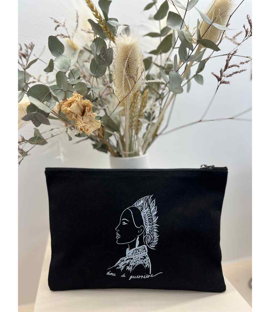 Pochette en coton bio noir. Le vêtement présente un imprimé blanc représentant une guerrière et une divinité japonaise, accompagnée de l’inscription « âme d'une guerrière ». Modèle Benten, conçu et imprimé à Lyon par la marque éthique Leonor Roversi.