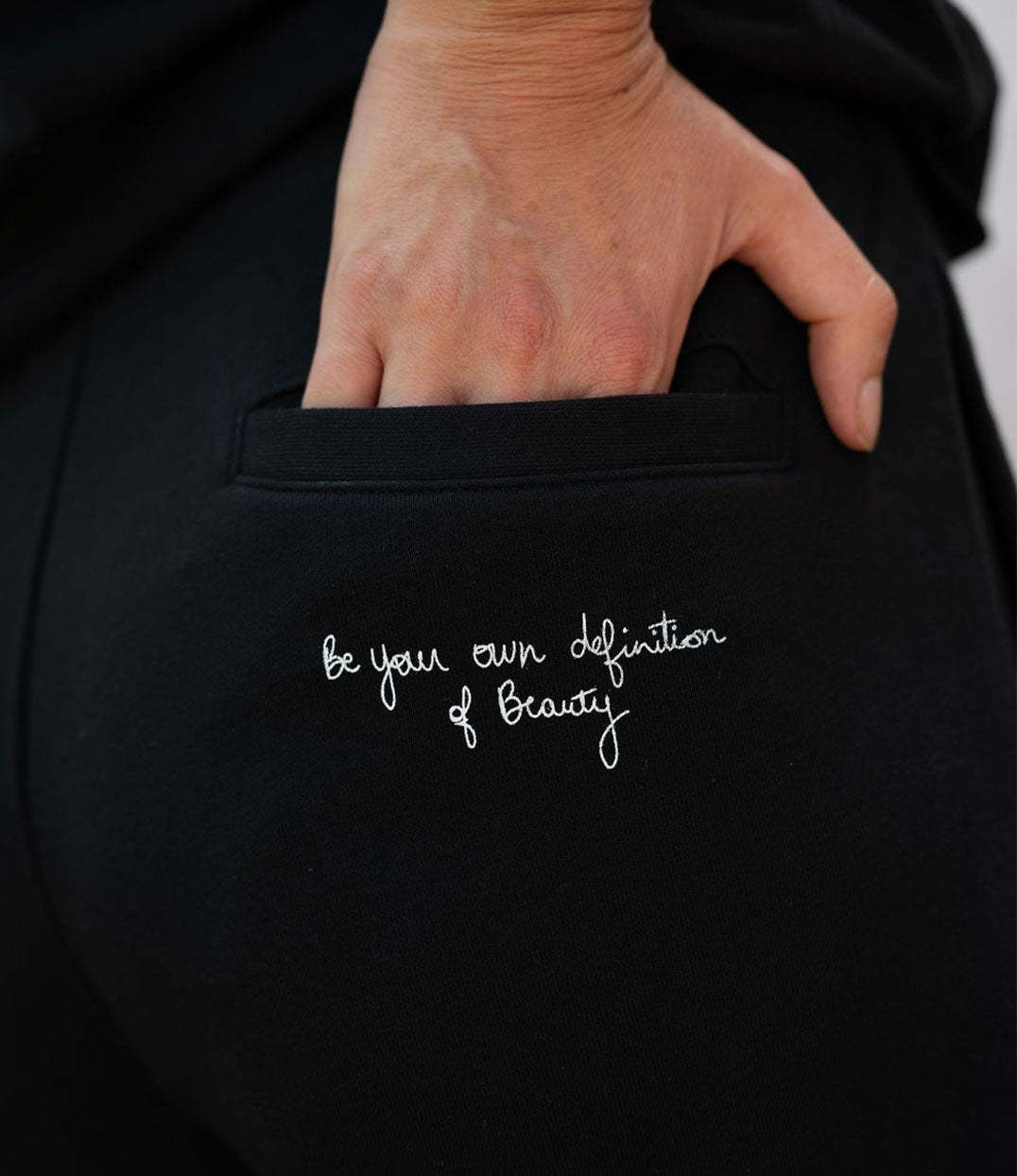 Gros plan sur un short pour femme en coton bio noir, avec une inscription manuscrite blanche "Be your own definition of beauty" à l'arrière. Modèle Sekhmet, imprimé à Lyon par la marque éthique Leonor Roversi.