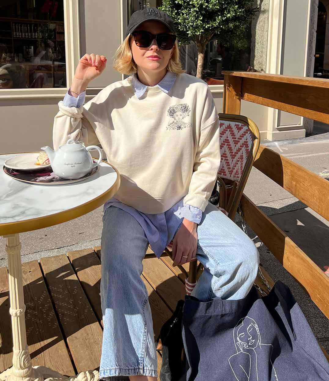 Femme portant un sweatshirt écru en coton biologique, imprimé noir d'une femme forte avec des fleurs dans les cheveux représentant la première reine nigériane accompagnée de l'inscription  "Valiente" sur le côté. Modèle Valiente conçu et imprimé à Lyon par la marque éthique Leonor Roversi.