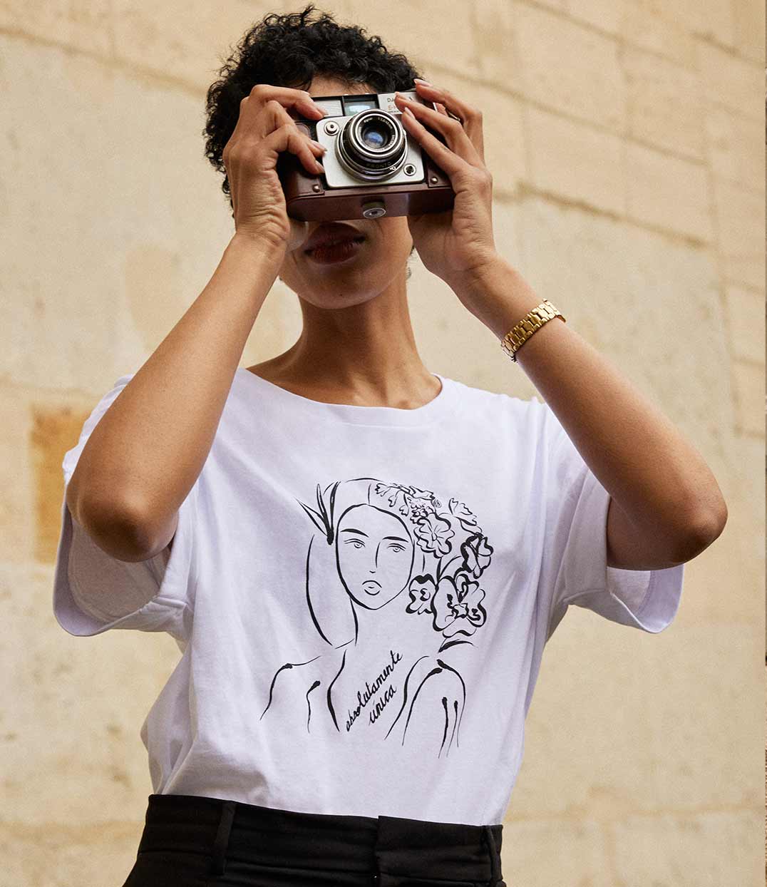 Gros plan sur un t-shirt en coton bio blanc, imprimé d'une femme au regard serein entourée de fleurs dans les cheveux accompagnée de l'inscription "Absolumente única". Modèle Unica, imprimé à Lyon par la marque éthique Leonor Roversi.