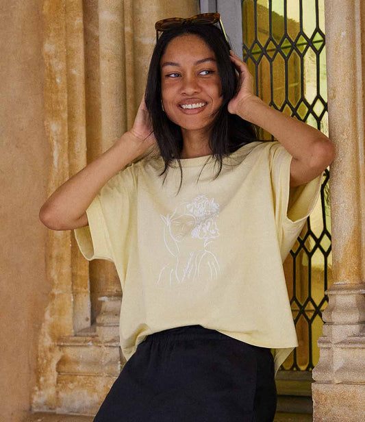 T-shirt femme en coton bio jaune, imprimé blanc d’une femme inspirée de la peintre impressionniste Mary Cassatt représentant une femme au regard serein entourée de fleurs dans les cheveux accompagnée de l'inscription "Absolumente única". Modèle Unica, conçu et imprimé à Lyon par la marque éthique Leonor Roversi.