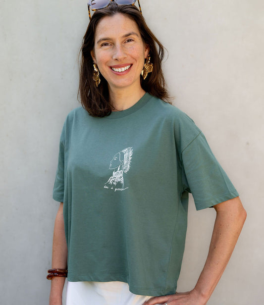 Femme portant un t-shirt ample en coton bio vert aloe. Le vêtement présente un imprimé blanc représentant une guerrière japonaise, accompagnée de l’inscription « âme d'une guerrière ». Modèle Benten, conçu et imprimé à Lyon par la marque éthique Leonor Roversi.