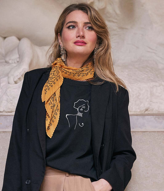 T-shirt ample noir pour femme en coton bio, porté face caméra, mettant en valeur le dessin blanc d’une femme forte symbole de courage et de résilience. Sérigraphie éco-responsable réalisée à Lyon par la marque lyonnaise Leonor Roversi.