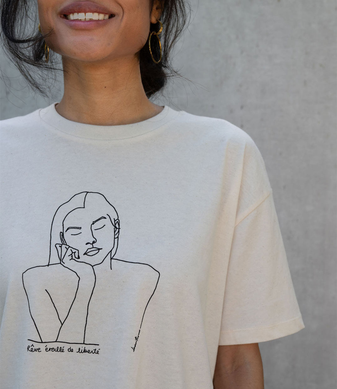 Gros plan sur un t-shirt femme en coton bio écru avec un imprimé noir d'une représentation de Thémis avec l'inscription "Rêve éveillé de liberté". Imprimé à Lyon par la marque éthique Leonor Roversi.