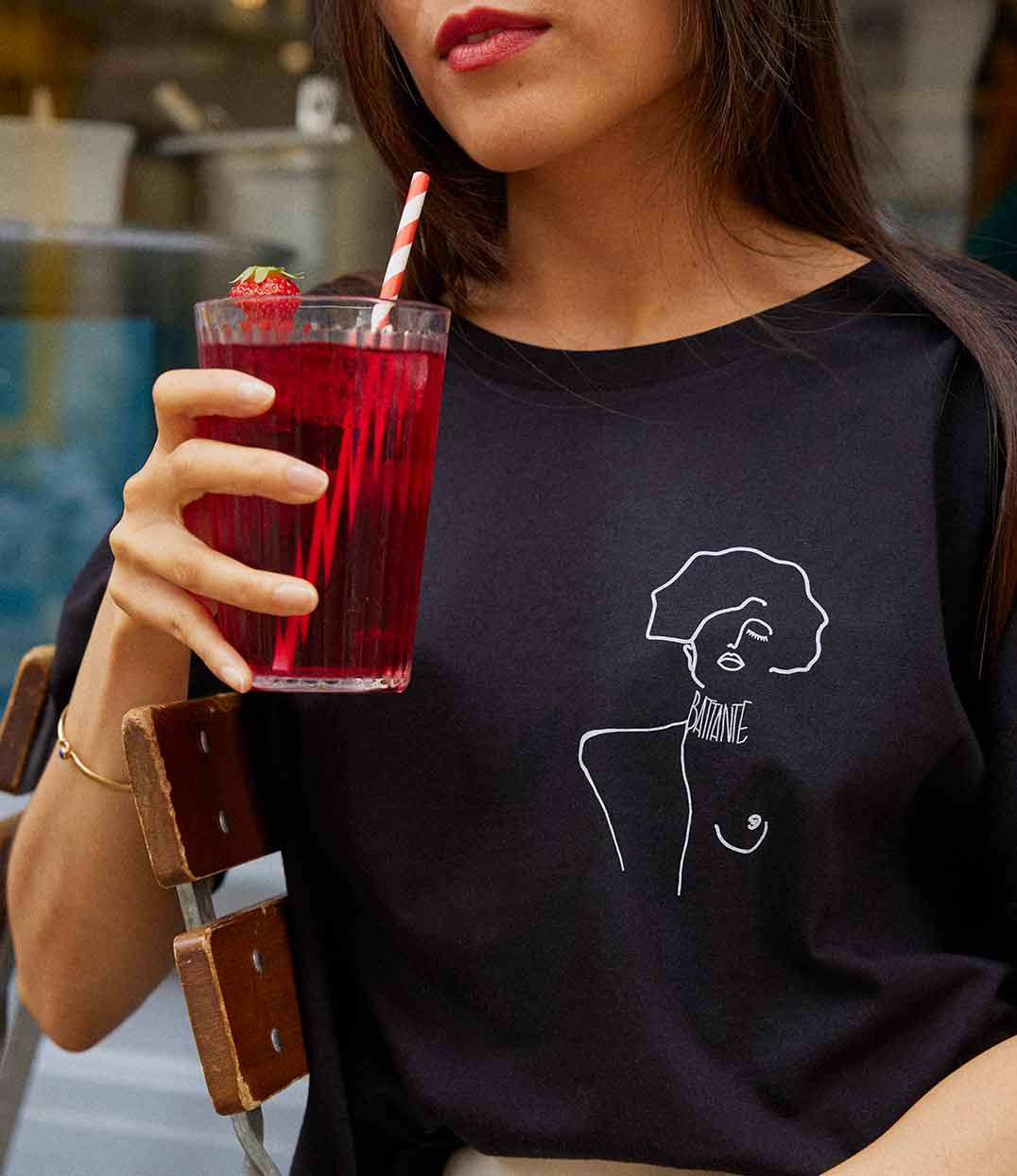 Gros plan sur une femme portant un t-shirt ample en coton bio noir, imprimé blanc d'une femme forte avec l'inscription "battante". Modèle Klimt, conçu et imprimé à Lyon par la marque éthique Leonor Roversi.