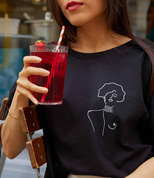 Gros plan sur une femme portant un t-shirt ample en coton bio noir, imprimé blanc d'une femme forte avec l'inscription "battante". Modèle Klimt, conçu et imprimé à Lyon par la marque éthique Leonor Roversi.