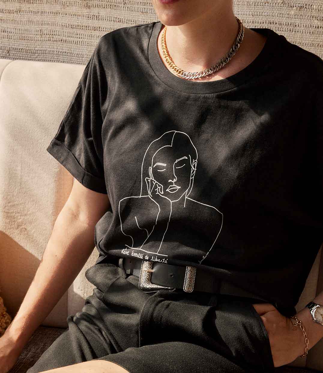 Gros plan sur un t-shirt femme en coton bio noir, imprimé blanc représentant la déesse Thémis, avec l'inscription manuscrite "Rêve éveillé de liberté". Conçu et imprimé à Lyon par la marque éthique Leonor Roversi.