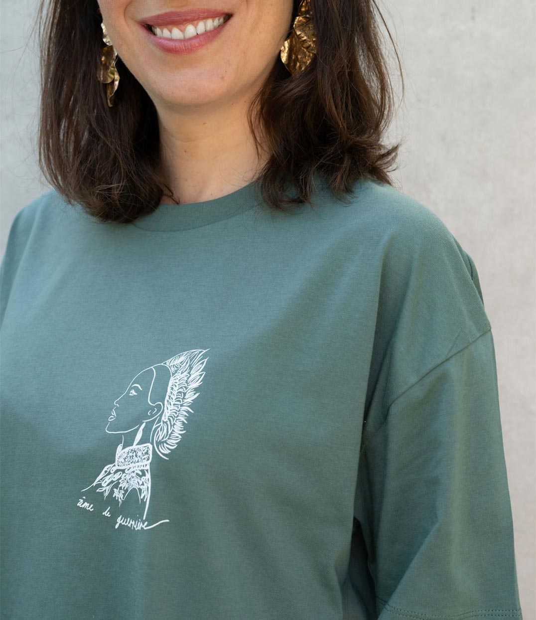 Gros plan sur un t-shirt femme en coton bio vert aloe, orné d'un imprimé blanc représentant une guerrière inspirée de la divinité japonaise Benzaiten, avec l'inscription manuscrite "âme de guerrière". Modèle Benten, imprimé à Lyon par la marque éthique Leonor Roversi.
