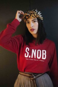 Photo d'une mannequin portant un sweat rouge, imprimé SNOB de la marque leonor roversi
