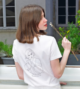 femme tenant une fleur elle porte un t-shirt blanc freyja de la marque leonor roversi