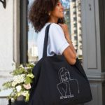 femme portant un t-shirt et un sac cabas noir de la collection reines de la marque lyonnaise féministe éthique et éco-responsable Leonor roversi