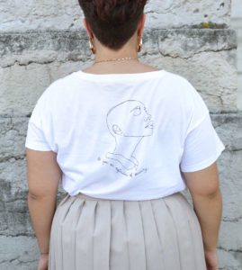 femme portant un t-shirt blanc avec le visuel représentant la déesse Sekhmet