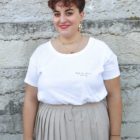 femme portant un t-shirt blanc avec une jupe et souriante