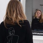 femme devant le miroir portant le sweatshirt themis noir de Leonor Roversi