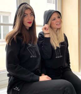 Deux femmes assises portant des Sweatshirt à capuche noir de la collection de Leonor Roversi