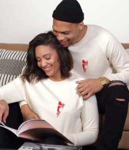 Un homme et une femme lisent un magazine en souriants. Ils portent tous les deux un sweat abracito leonor roversi
