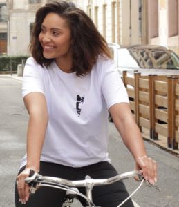 Une femme brune fait du vélo. Elle sourie et porte le tshirt abracito coeur noir en coton biologique leonor roversi