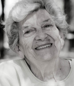 Une grand-mère regarde l'objectif en souriant, la photo est en noir et blanc.