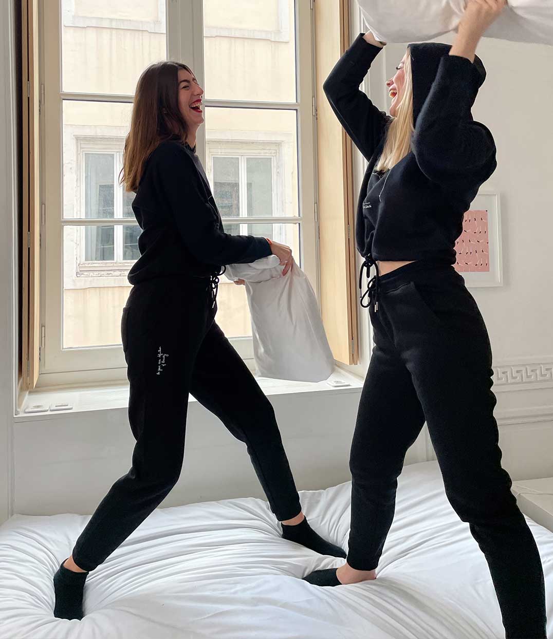 Deux femmes portant des sweats à capuche et joggings noir de la collection de Leonor Roversi