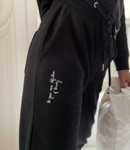 Femme portant un jogging noir avec inscription en blanc sur le côté de la marque Leonor Roversi