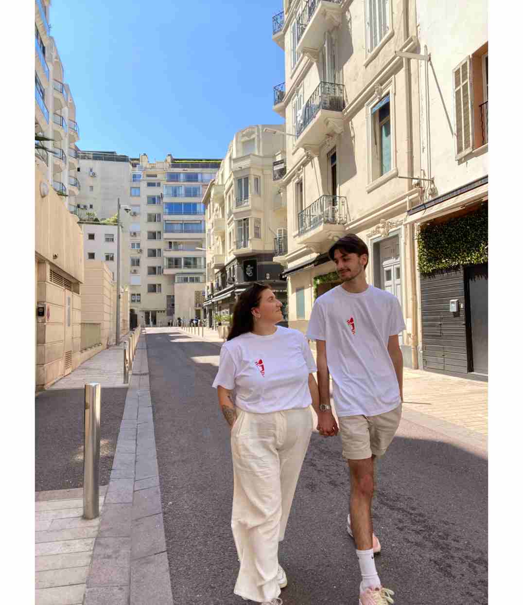Un couple qui marche portant le tshirt blanc abracito rouge de leonor roversi